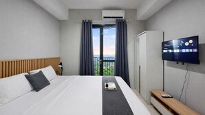 Hotellihuone, jossa on sänky, televisio, työpöytä ja näkymä ulos.