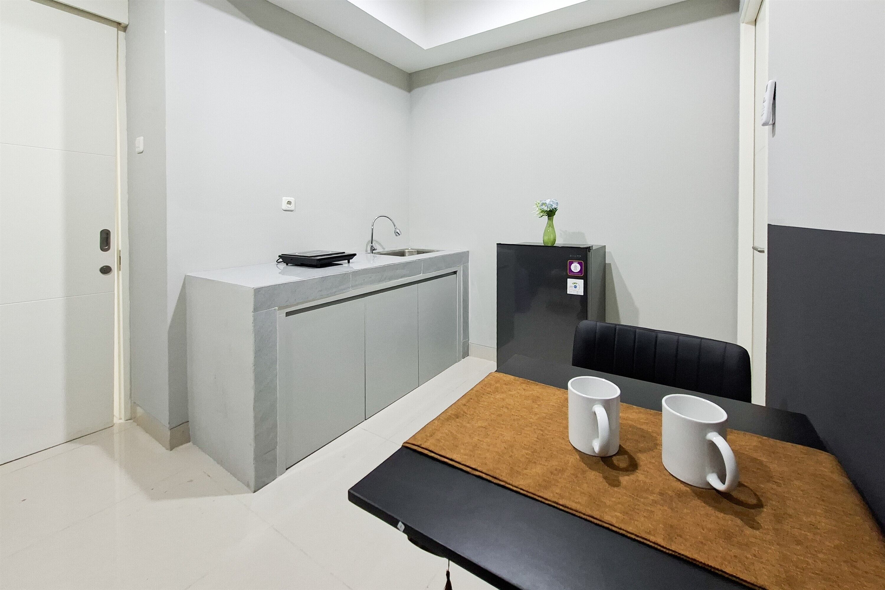 Une cuisine compacte comprenant un évier, un petit réfrigérateur et un coin repas avec une table et des chaises.