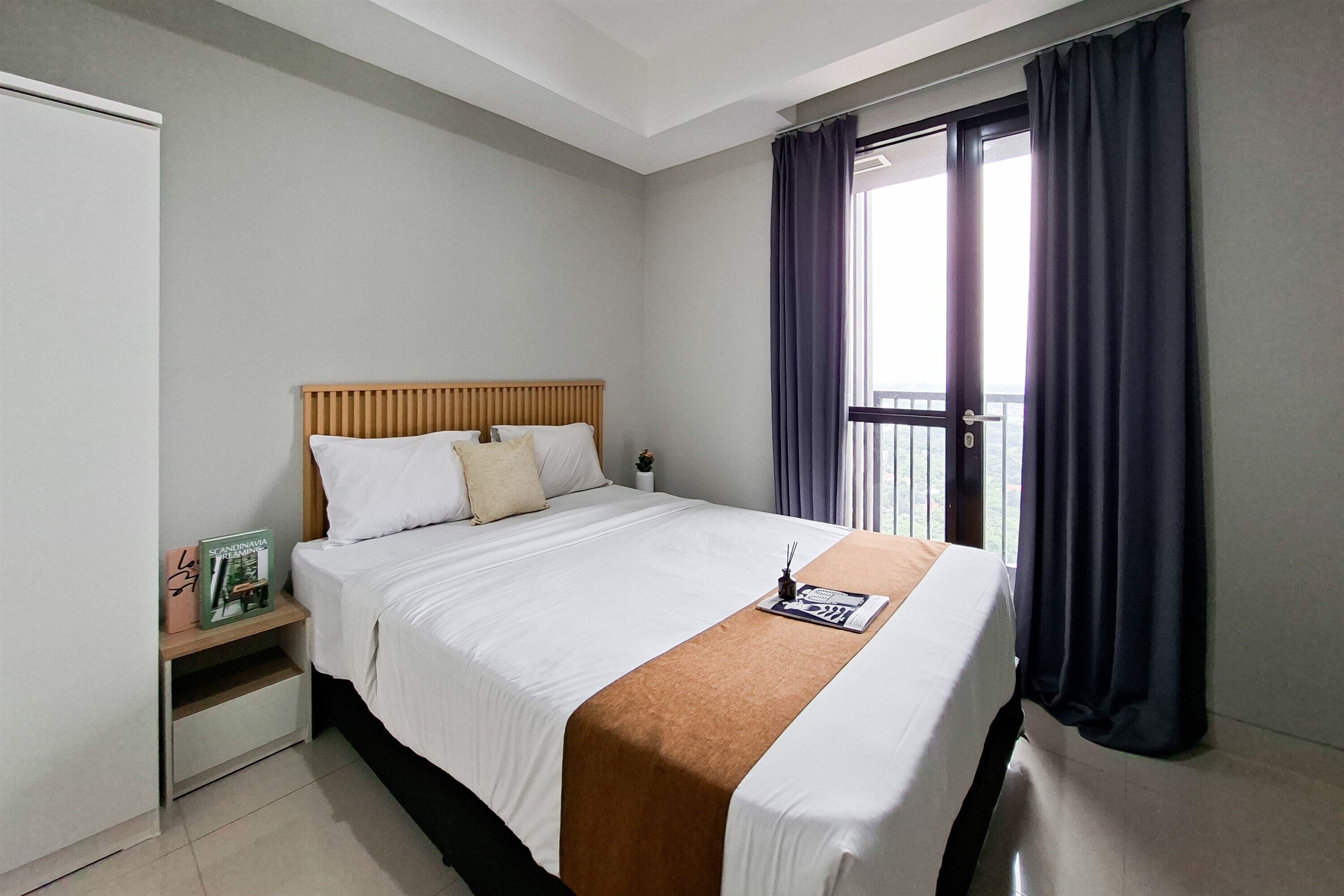 Una camera d'hotel con un letto, un comodino, una finestra con tende e vista sulla città.