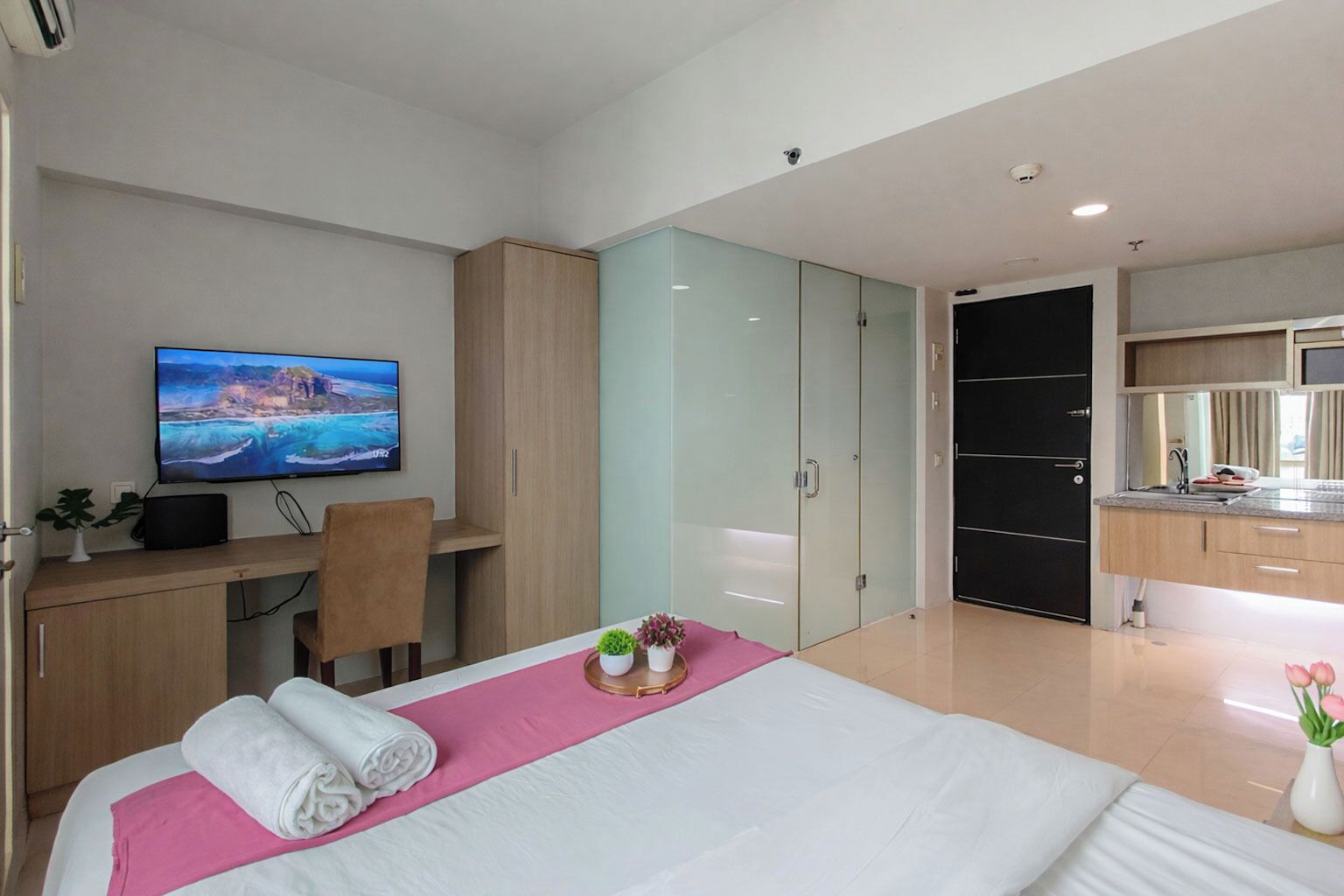 Een moderne hotelkamer met een bed, een bureau, een televisie, een kledingkast en een badkamer.