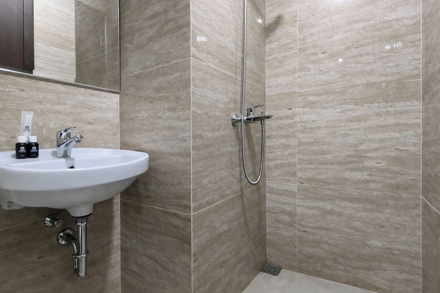 A bathroom with a sink, mirror, and shower.