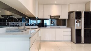 A modern kitchen with white cabinetry, a built-in dishwasher, and a black refrigerator. - Spacious And Lavish 4Br At The Via And The Vue Ciputra World Apartment (Surabaya)