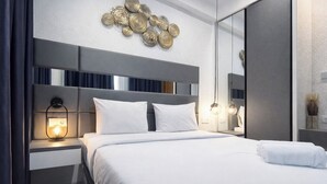 Una habitación de hotel moderna con una cama grande, una mesita de noche con lámpara, un adorno de pared y un espejo.