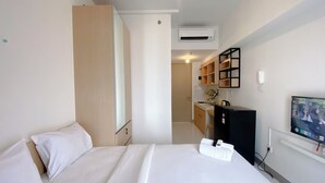 Et hotelværelse med seng, skrivebord, stol, fjernsyn og aircondition.