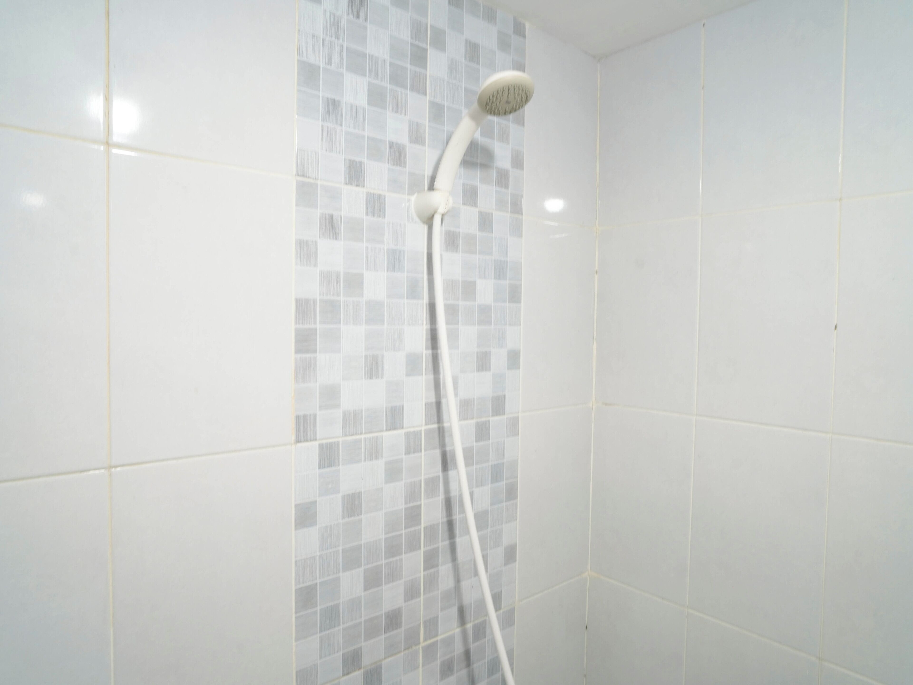 A shower with a grey-tiled wall and a white showerhead.
