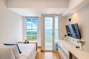 Een slaapkamer met een bed, een televisie, een raam met uitzicht en een deur.