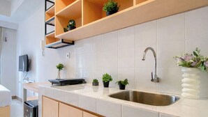 Una cocina moderna con un lavamanos de acero inoxidable, armarios de madera, un estante empotrado con plantas en macetas y un televisor de pantalla plana montado en la pared.