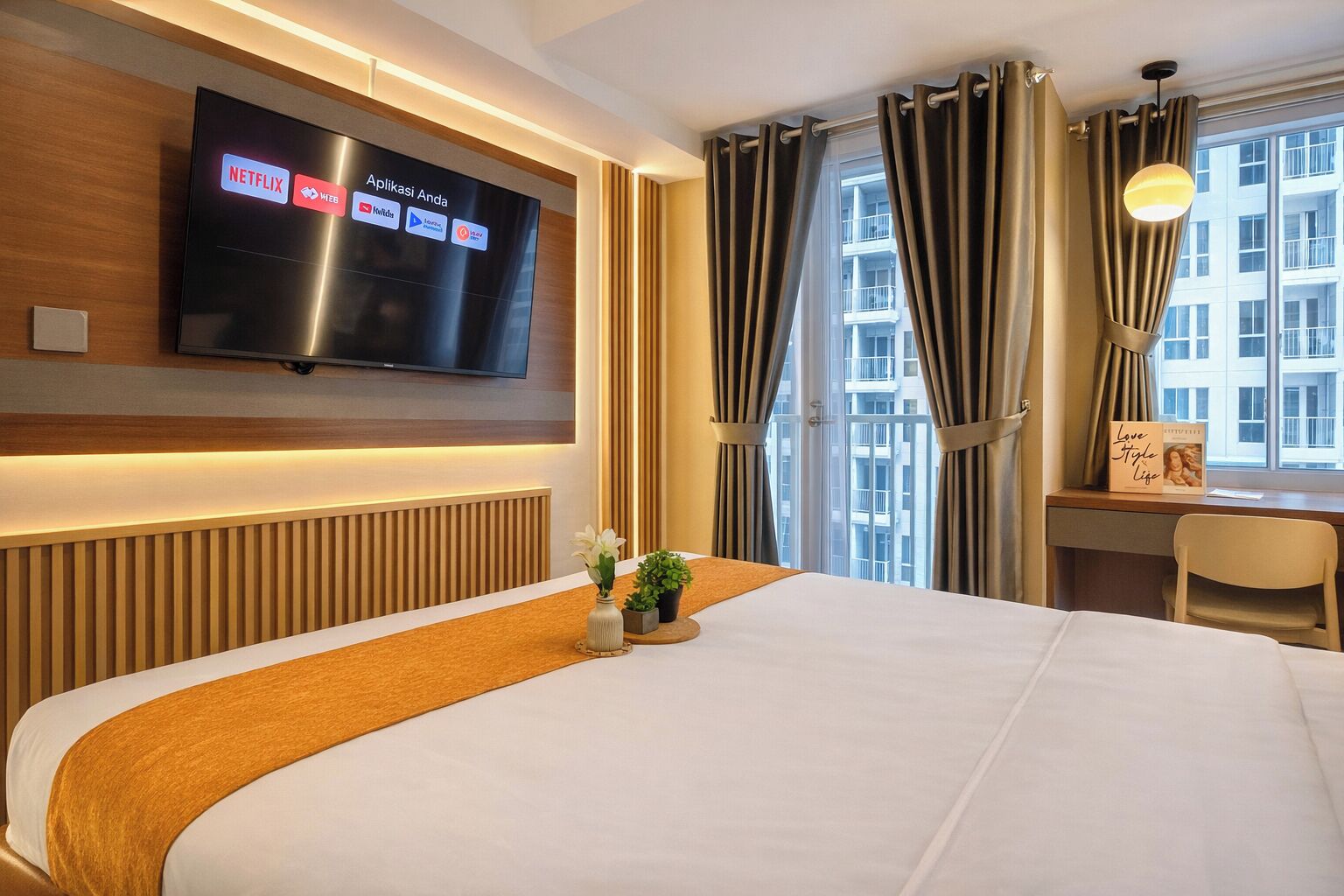 Quarto de hotel com cama, TV fixada na parede exibindo vários ícones de aplicativos, escrivaninha com cadeira e janela com cortinas.