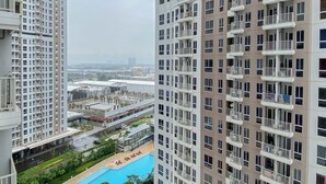 A high-rise residential building with multiple balconies, a rooftop pool, and a view of the surrounding urban area. - Nice Space And Pleasant Studio At Apartment Tokyo Riverside Pik 2 (Teluknaga)