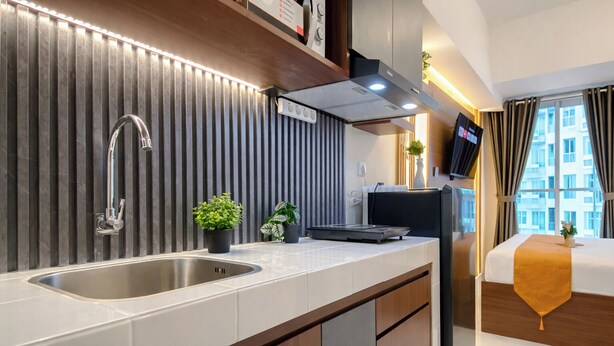 A modern kitchenette with a stainless steel sink, a built-in stove, and a flat-screen TV mounted above the counter. - Nice Space And Pleasant Studio At Apartment Tokyo Riverside Pik 2 (Teluknaga)
