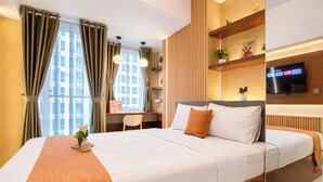 A hotel room with a large bed, a desk, a TV, and a view of the city. - Nice Space And Pleasant Studio At Apartment Tokyo Riverside Pik 2 (Teluknaga)