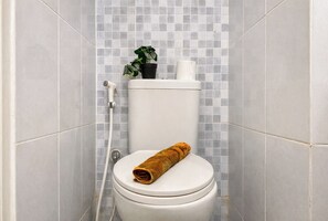 Et badeværelse med toilet, bruser og fliserede vægge.