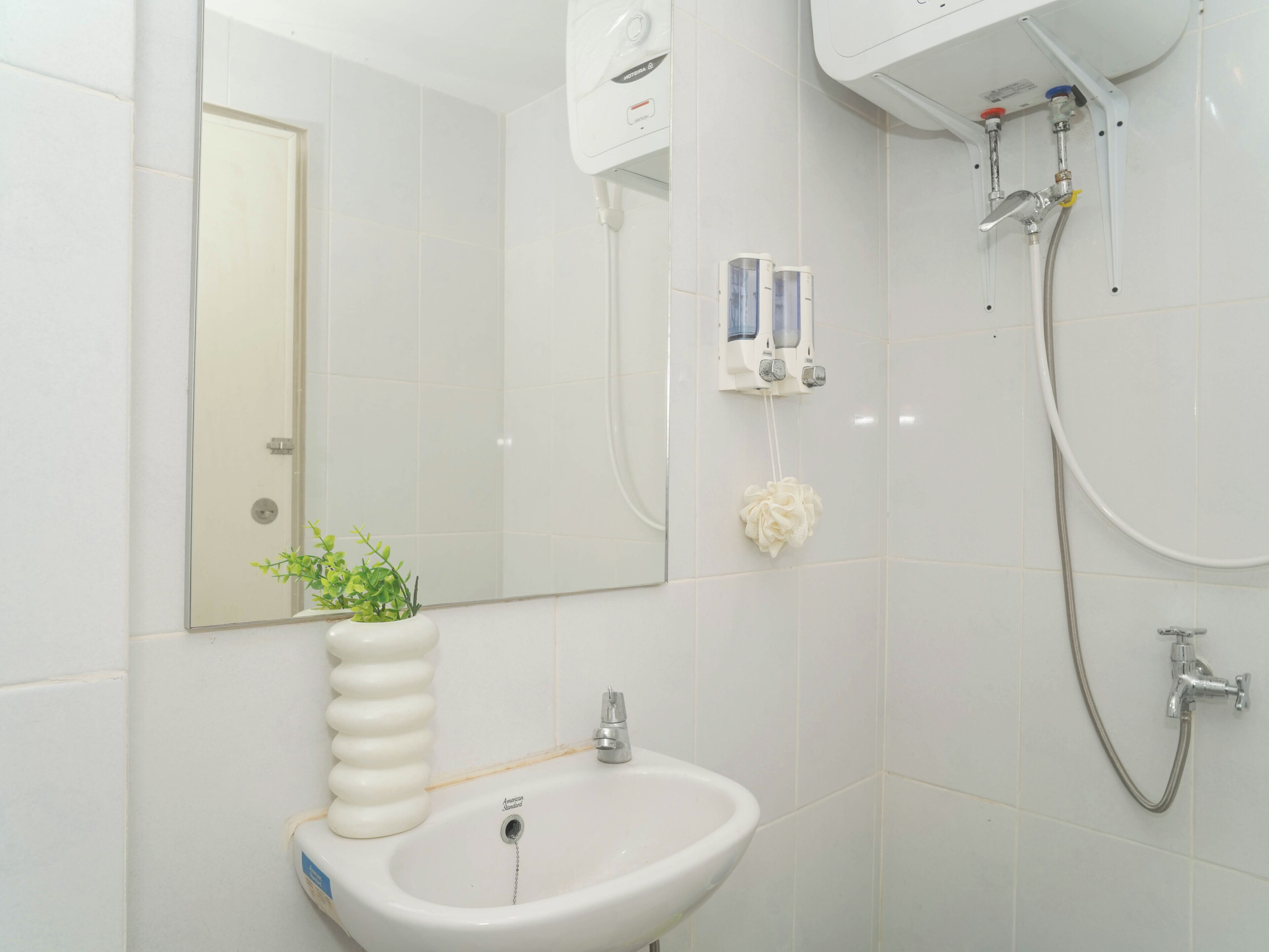 A bathroom with a sink, mirror, shower, and toiletries.