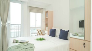 Een slaapkamer met een bed, een kledingkast, een bureau, een stoel, een raam en een balkon.
