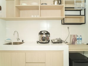 A kitchen with a stainless steel sink, a kettle, a rice cooker, and a countertop with a water dispenser. - Strategic And Stylish Studio At Apartment Tokyo Riverside Pik 2 (Teluknaga)
