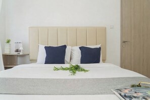 A bed with a headboard, two pillows, a bedside table with a lamp, and a door. - Functional 2Br For 3 Pax At Tokyo Riverside Pik 2 Apartment (Teluknaga)