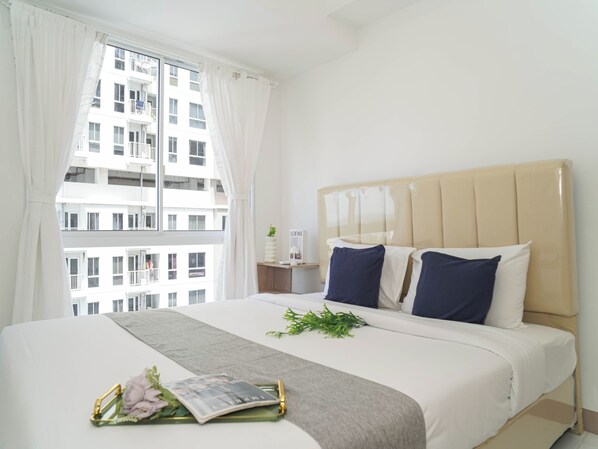 A hotel room with a large bed, a window with curtains, a bedside table with a plant, and a view of a building outside. - Functional 2Br For 3 Pax At Tokyo Riverside Pik 2 Apartment (Teluknaga)