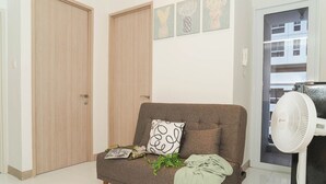 Een woonkamer met een bank, een ventilator en een deur.