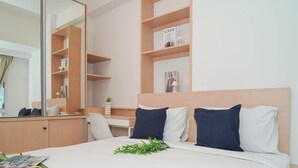 Ein Hotelzimmer mit einem Bett, einem Schreibtisch, einem Stuhl, einem Spiegel und einem Regal mit Büchern und Dekoration.
