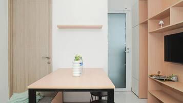 A modern kitchen with a wooden table, two chairs, a bench, a TV, and a shelf with decorative items.