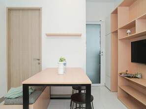 Eine moderne Küche mit einem Holztisch, zwei Stühlen, einer Bank, einem Fernseher und einem Regal mit Dekoration.