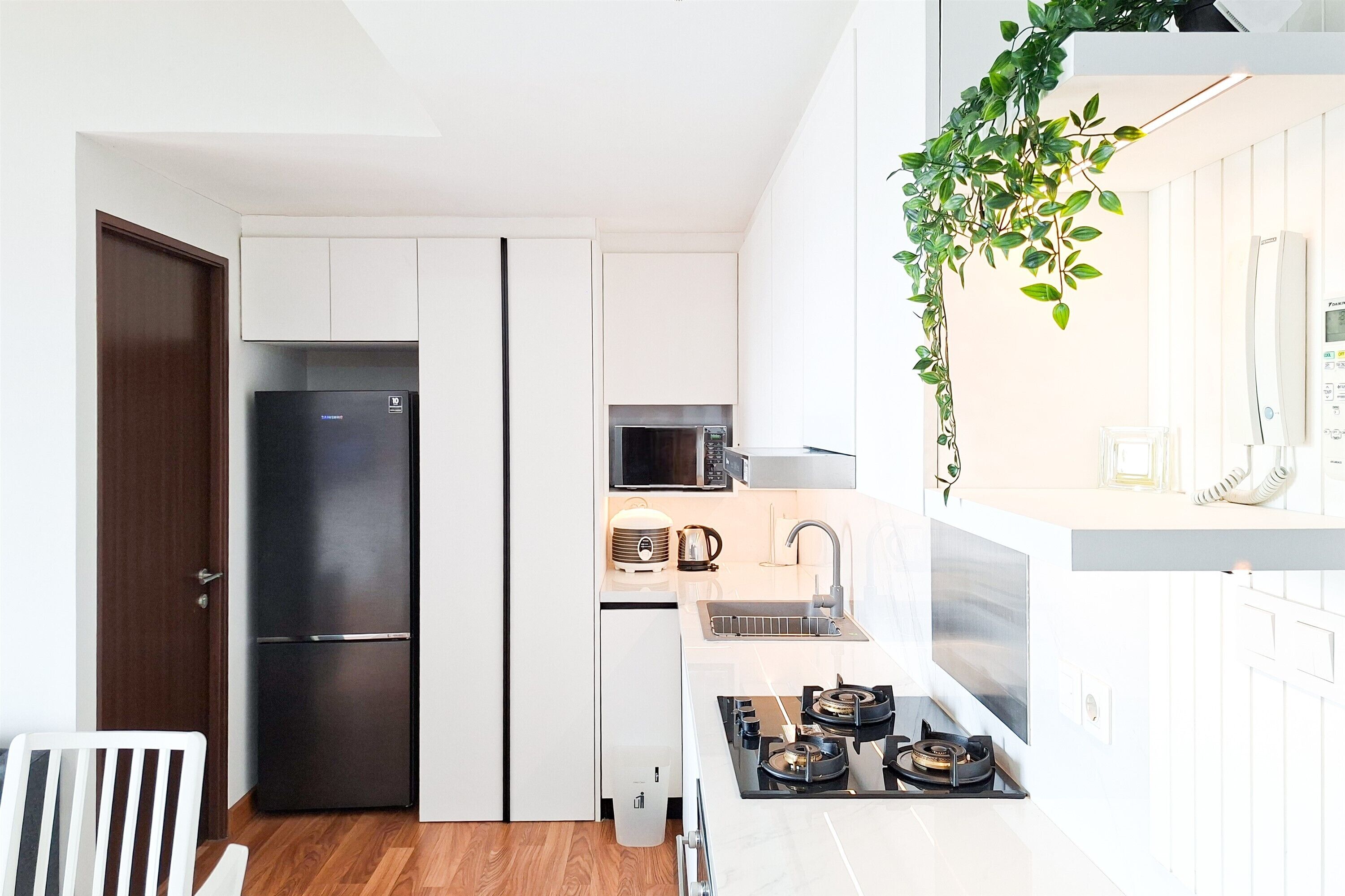 A compact kitchen with a refrigerator, microwave, sink, and stove.
