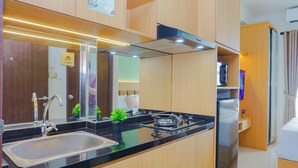 A modern kitchen with a sink, stove, and refrigerator, wooden cabinets, and a large mirror. - Soft Toned Studio At Transpark Cibubur Apartment (Depok)