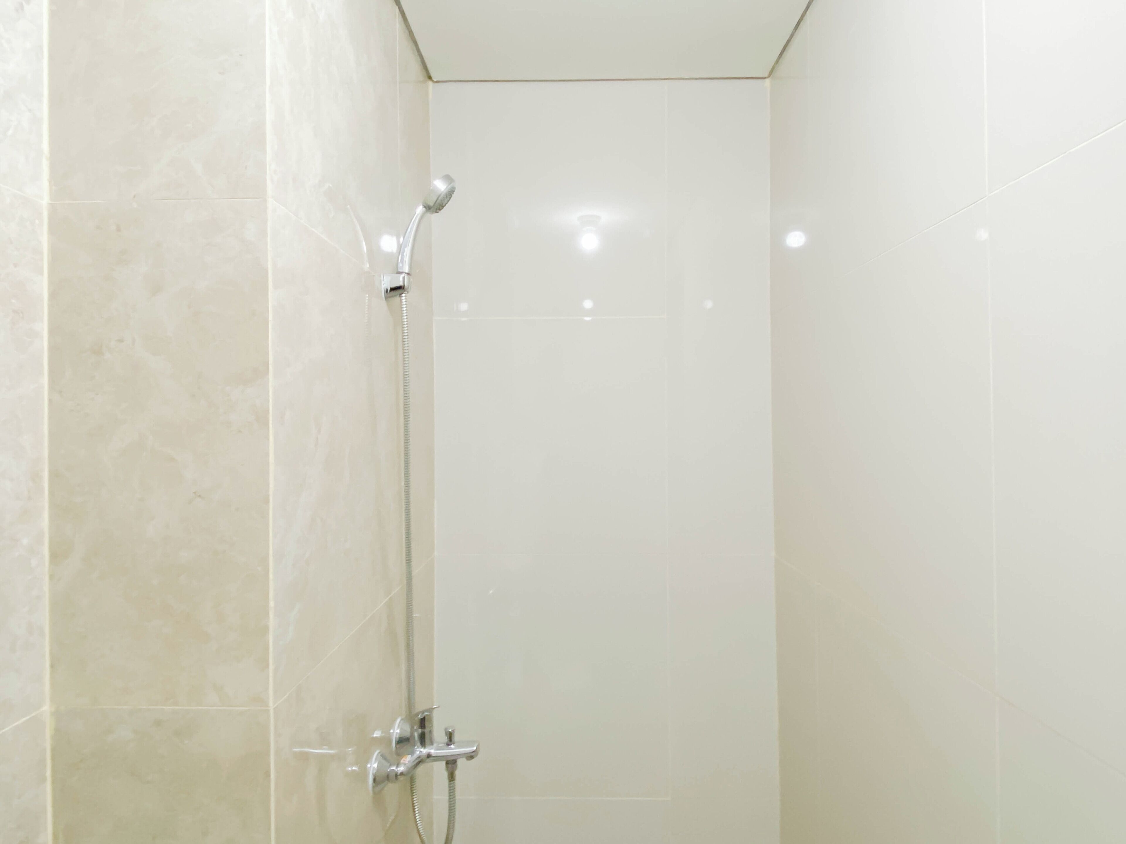 A shower with a handheld showerhead and a wall-mounted faucet.