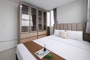 Una habitación de hotel con cama, un armario grande y ventana con cortinas.