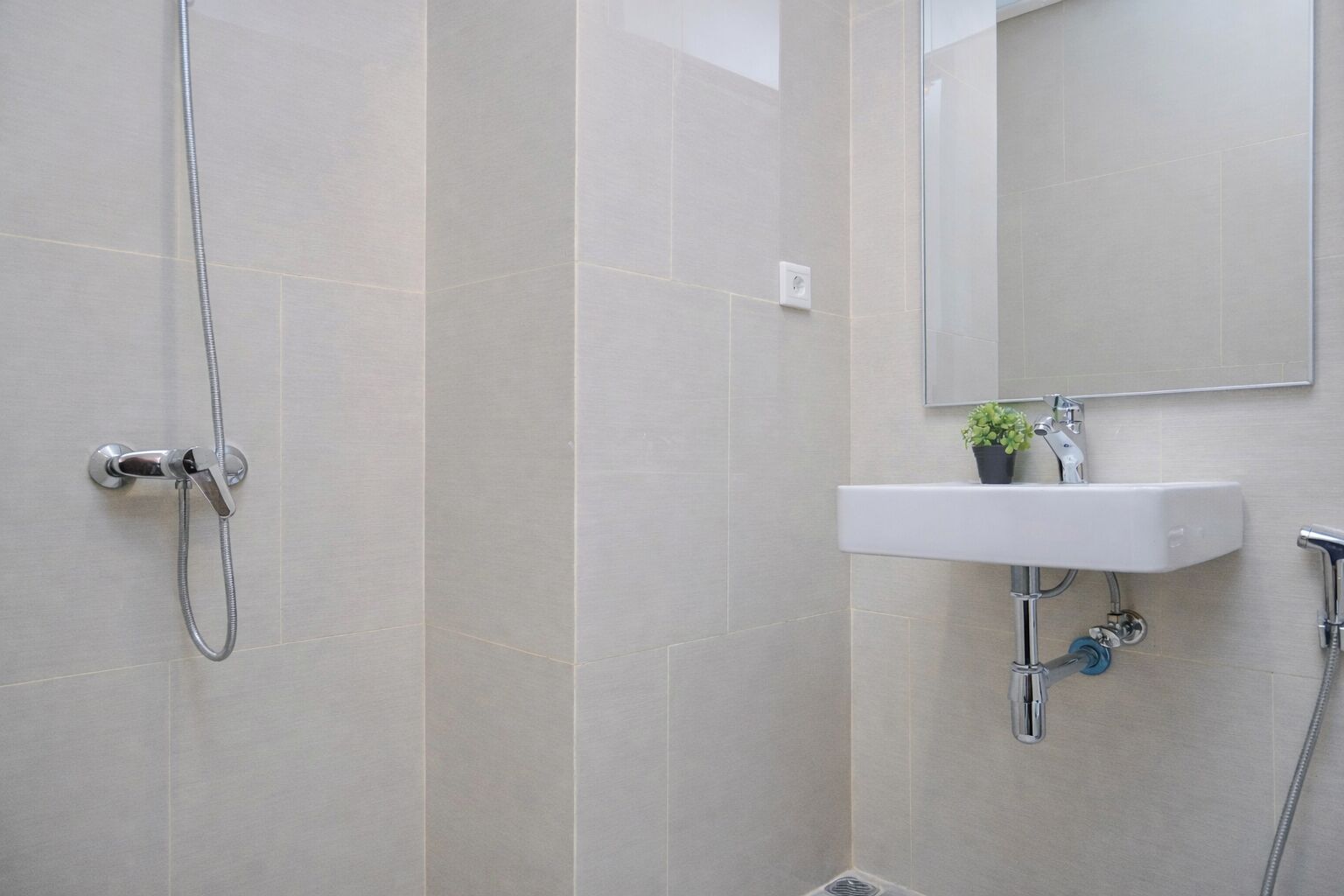 Ein Badezimmer mit Dusche, Waschbecken und Spiegel.