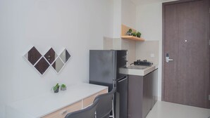 Una cocina compacta con refrigerador, una encimera y un estante de madera con plantas.