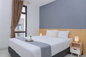 A hotel room with a bed, bedside tables, a window with curtains, and a view of buildings outside. - Tranquil Studio At Vasaka Solterra Apartment (Jakarta)