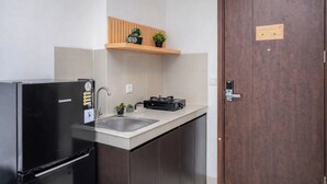 Una cocina compacta con refrigerador, pileta y repisa de madera sobre la encimera.
