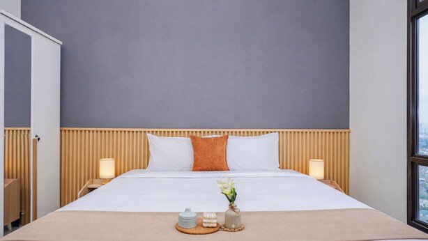 Habitación de hotel con cama, dos lámparas de noche, ventana y vista a la ciudad.