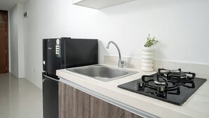 Eine moderne Küche mit einem schwarzen Kühlschrank, einer Edelstahl-Spüle und einem Gasherd.
