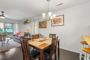 A dining area with a wooden table, chairs, and a chandelier. - Harborside 201: Charming Condo Steps from the Beach (Myrtle Beach)