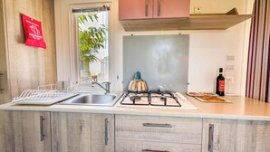 Une cuisine moderne dotée d’un évier en acier inoxydable, d’une cuisinière à gaz et d’armoires en bois.
