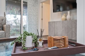 A tray with a potted plant, a bottle of essential oil, and a stack of coasters on a table. - CasaATX: Where Austin living meets comfort and style (Austin)