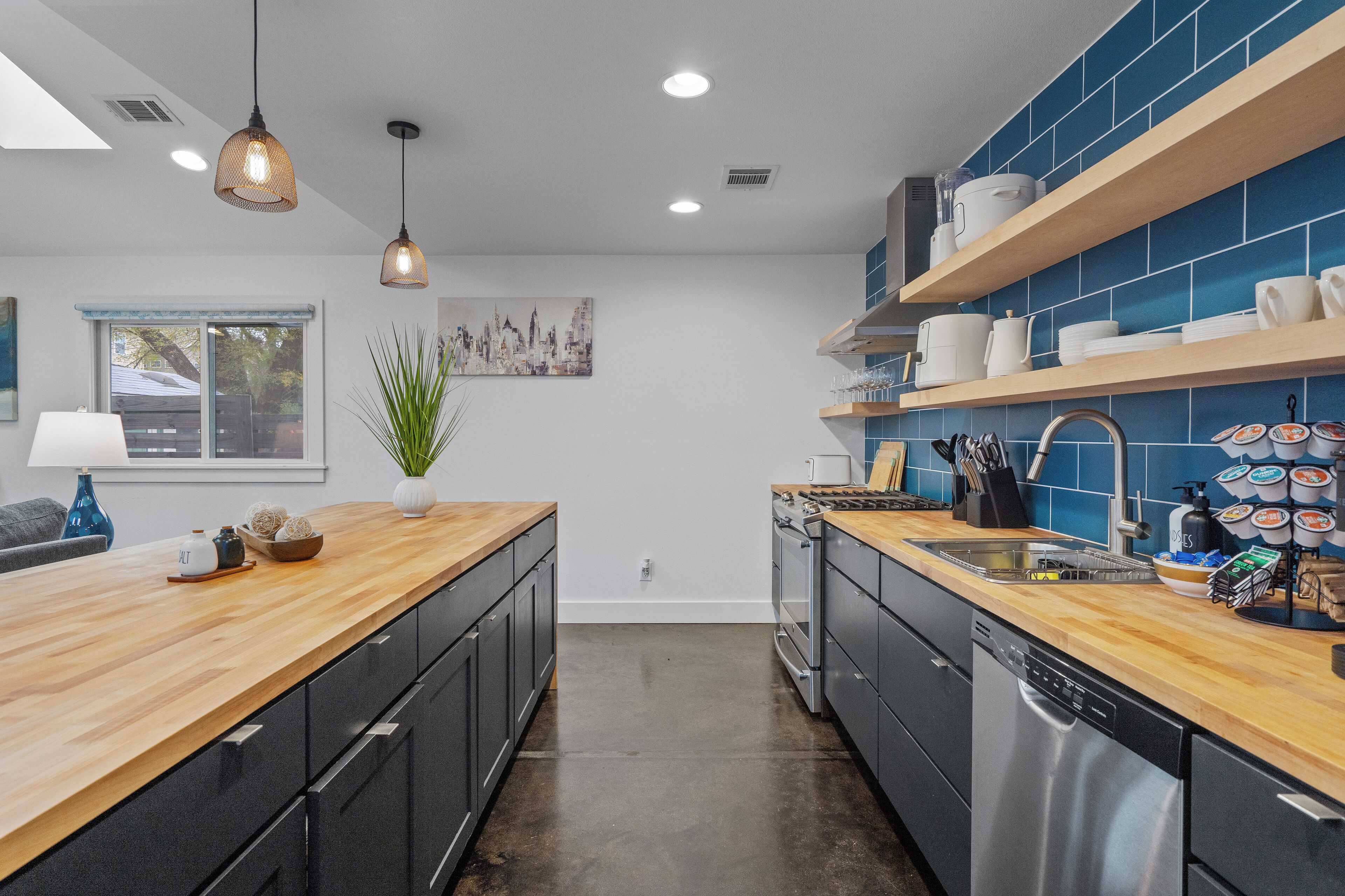 Una cocina moderna con encimeras de madera, armarios negros y salpicadero de azulejos azules.