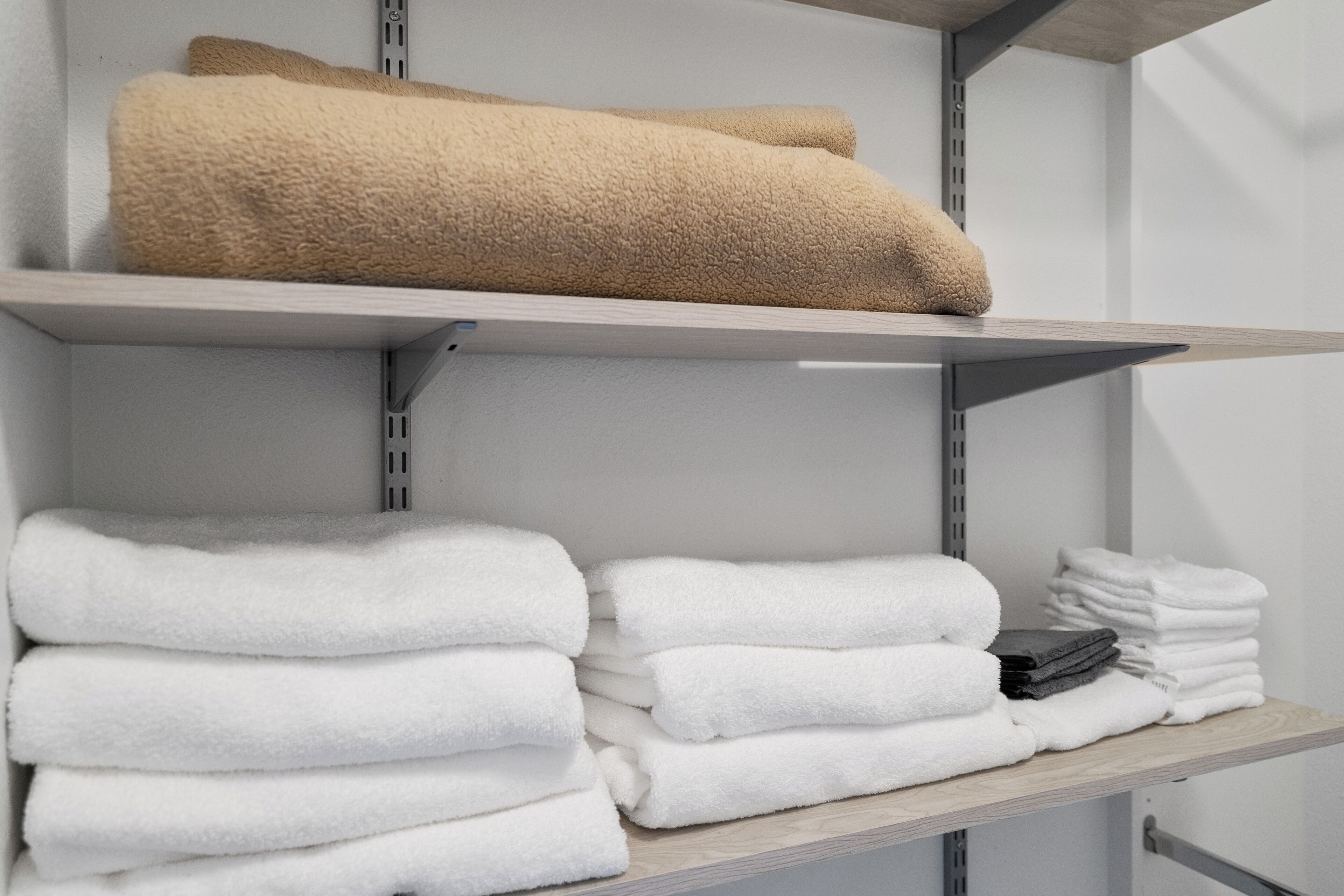 Une étagère de rangement avec des serviettes pliées avec soin, de couleur blanche et beige.
