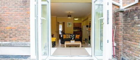 Une entrée moderne avec des portes vitrées donnant sur un espace de vie comprenant un canapé, une table basse et des objets décoratifs.