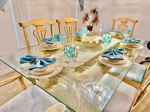 A dining table set with plates, glasses, and napkins, surrounded by wooden chairs. - 4 miles to Disney, 4 bed. Private Pool +Spa. King Triton’s Theme,  Free Snacks. (Kissimmee)