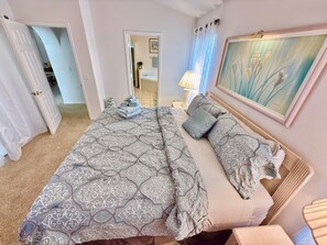 A bedroom with a bed, pillows, a bedside table, a lamp, and a painting on the wall. - 4 miles to Disney, 4 bed. Private Pool +Spa. King Triton’s Theme,  Free Snacks. (Kissimmee)