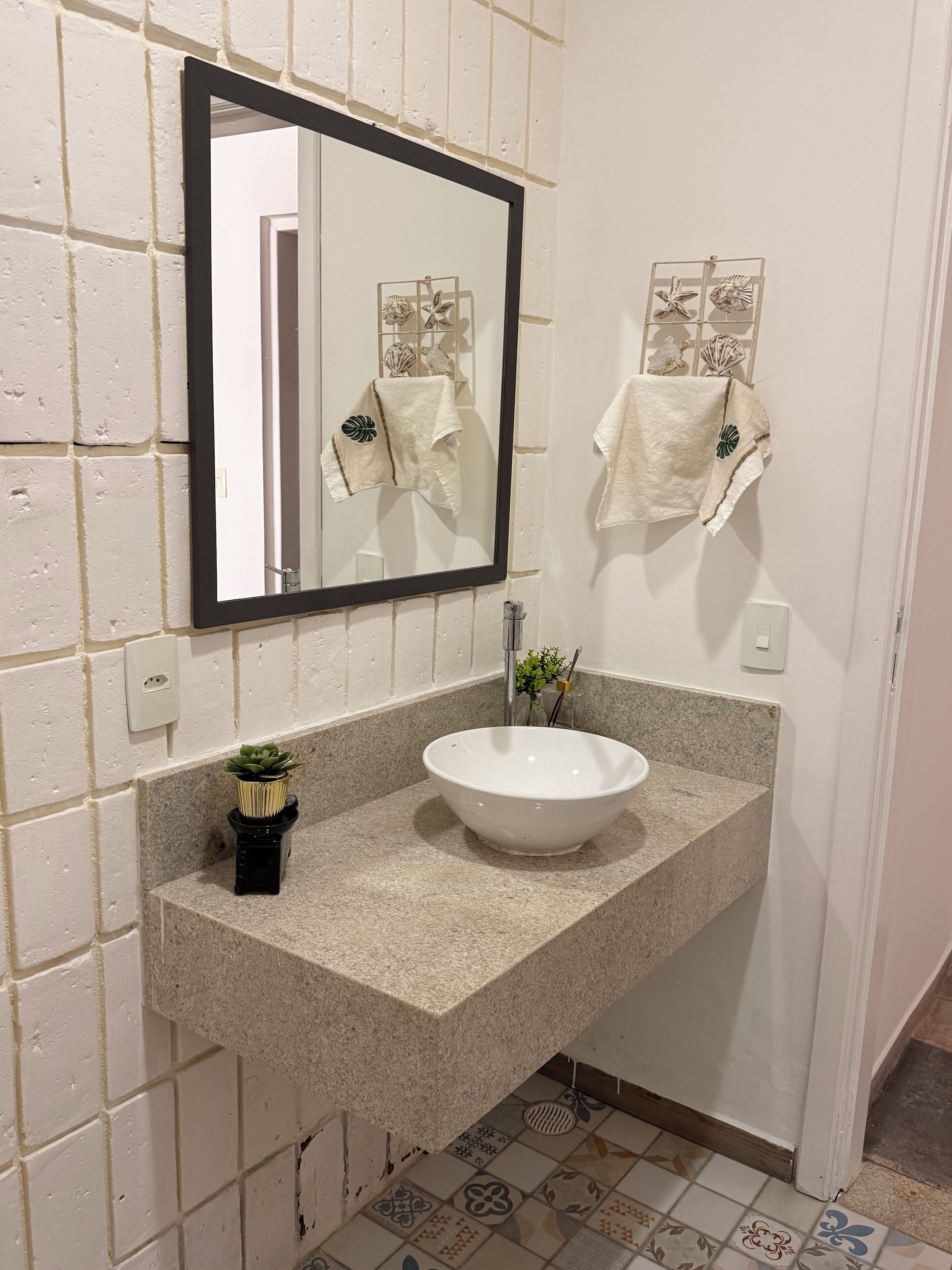 A bathroom with a white sink, a mirror, and a potted plant.
