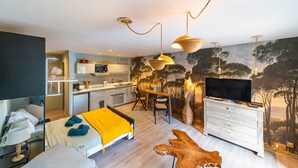 Quarto de hotel moderno com cama, escrivaninha, televisão e cozinha.