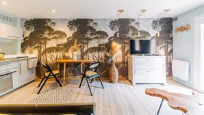 Uma cozinha moderna com área de refeições, TV e um mural com árvores.