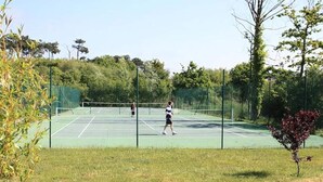 A tennis court surrounded by trees and grass. - Apartment in Soulac-sur-mer Near Beach (Soulac-sur-Mer)