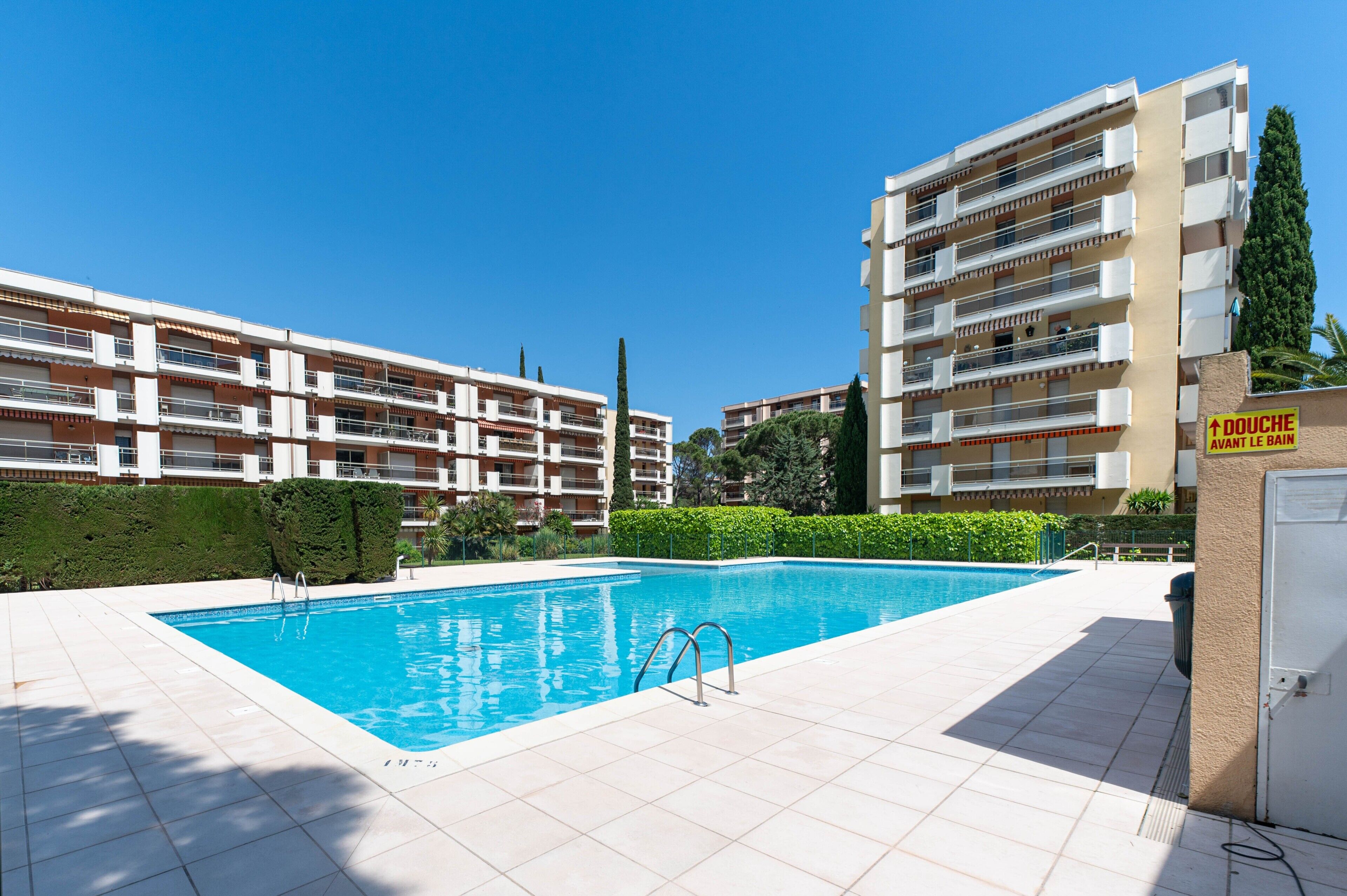 A swimming pool with a clear blue water, surrounded by a tiled deck.