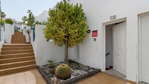 A staircase leading to a white door with a number sign, a cactus, and a small tree. - Vacation Apartment 'Vista Golf' with Sea View, Shared Pool and Wi-Fi (Mogán)