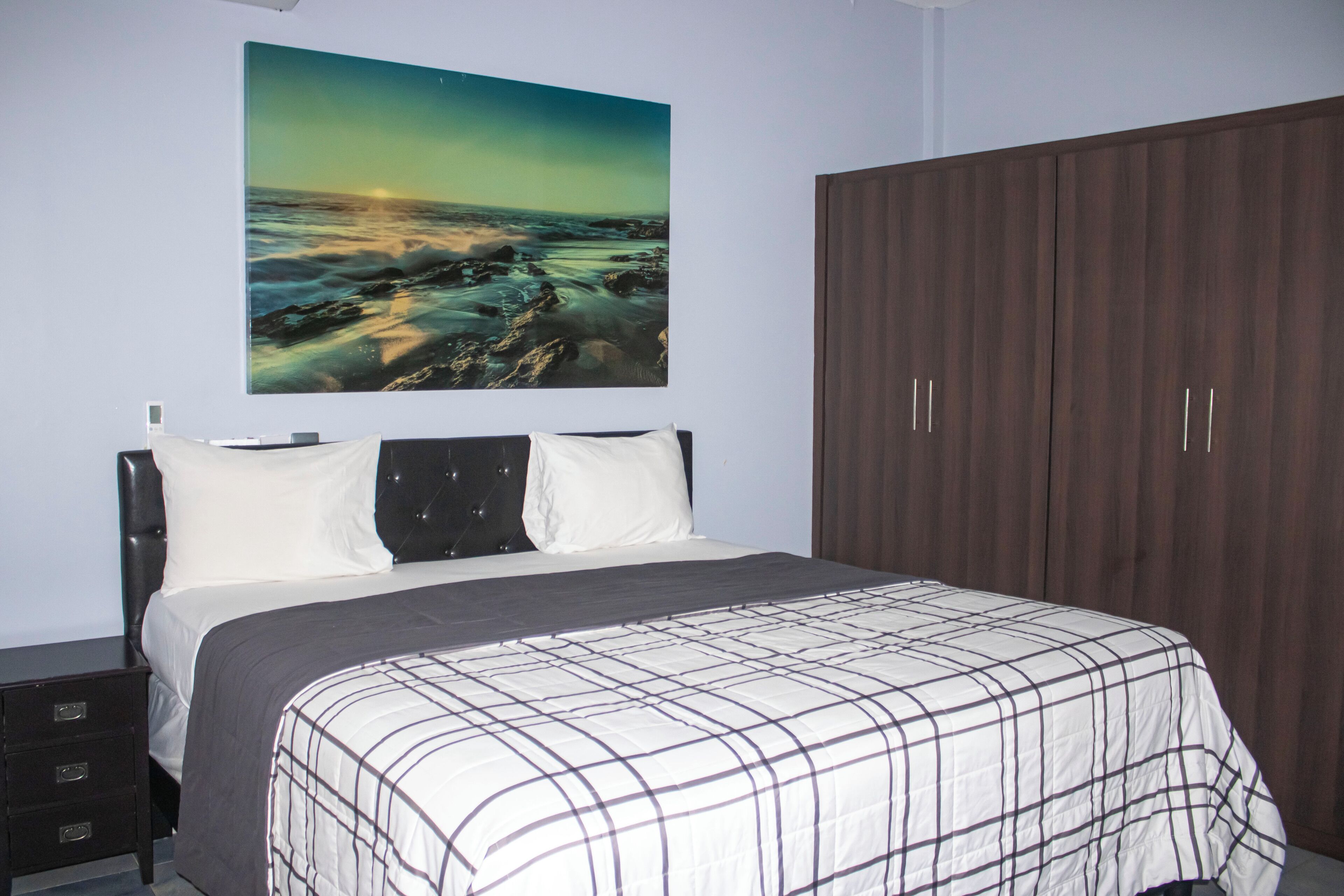 A bedroom with a bed, a wardrobe, and a wall-mounted painting.